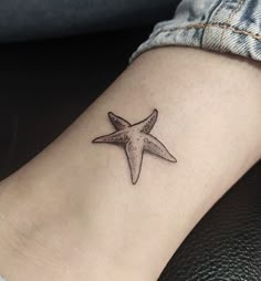 a small starfish tattoo on the ankle is shown in black and grey ink,