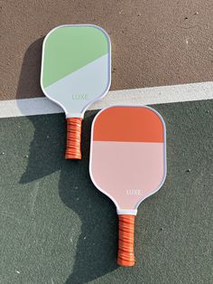 two tennis racquets sitting side by side on the ground next to each other