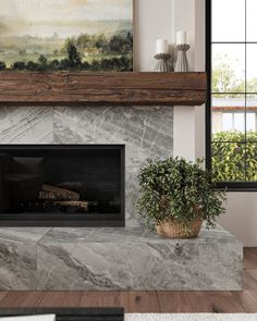 a living room with a fire place and painting on the wall above it, next to a potted plant