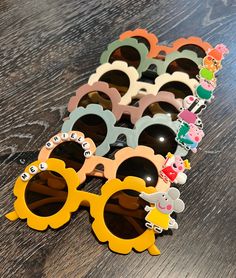 several pairs of sunglasses with cartoon characters on them sitting on a wooden table next to each other