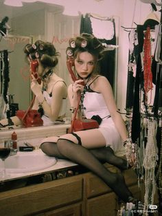 a woman sitting in front of a mirror with her legs up on the counter while holding a red purse