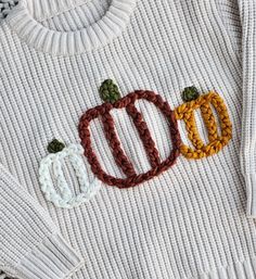 a white sweater with two pumpkins on the front and one is knitted to look like yarn