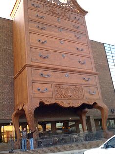 a tall wooden clock tower sitting on the side of a building next to a parking lot