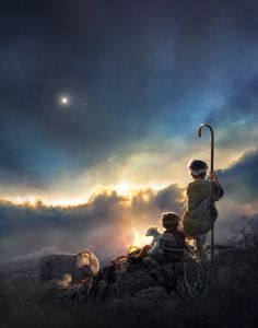 two children sitting on top of a hill watching the sun set with an umbrella over them