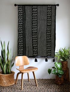 a wooden chair sitting in front of a black and white wall hanging on a wall