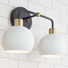 two light fixtures mounted on a white brick wall