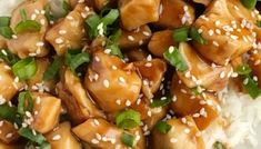 a white plate topped with chicken covered in sesame seeds and garnished with green leaves