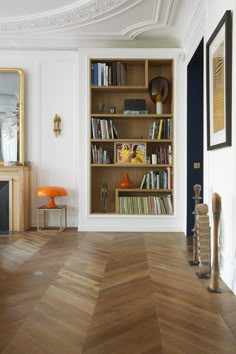 a living room filled with furniture and bookshelves on top of wooden flooring