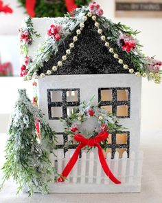 a white house with a red bow and wreath on the front is decorated for christmas