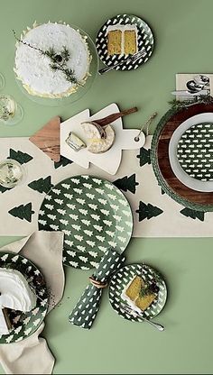 a table topped with green and white plates covered in cake next to slices of cake