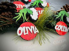 christmas cookies decorated with green and red icing on top of pine cones next to evergreen branches