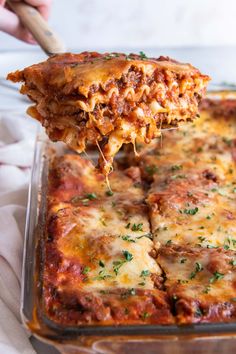 a slice of lasagna being lifted from a casserole dish with meat and cheese