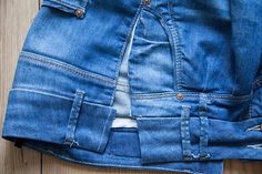 an old pair of blue jeans with holes in the back and side pockets, sitting on a wooden surface