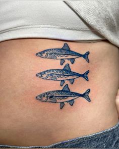 a woman's stomach with three fish tattoos on her belly and the bottom part of her stomach