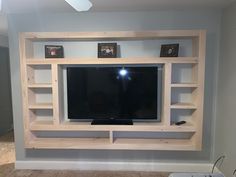 a flat screen tv mounted to the side of a wooden entertainment center in a living room