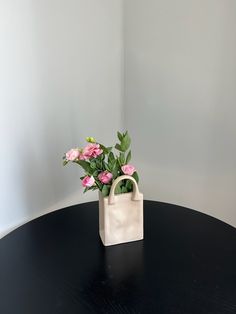 a white bag with pink flowers in it on a black table