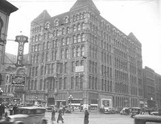 an old black and white photo of people walking in front of a large building on a city street