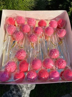 a box filled with lots of pink lollipops on top of plastic wrappers