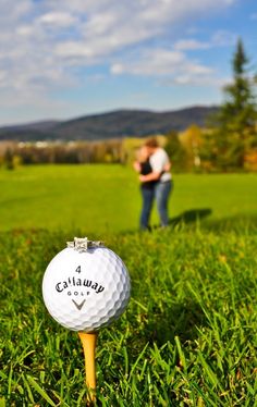 a golf ball sitting on top of a tee in the grass next to a man