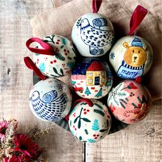 an arrangement of painted eggs in a bowl on a wooden table with red ribbon around them