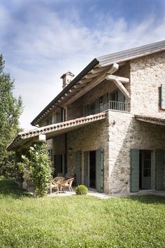 a stone house with a table and chairs in the front yard