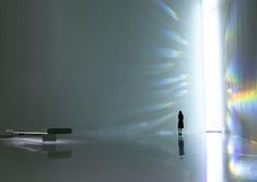 a person standing in an empty room with sunlight streaming through the walls and casting long shadows on the floor