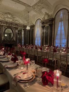 the tables are set with white linens and red rose centerpieces on them