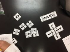 a black table topped with lots of different types of letters and numbers next to a person's hand