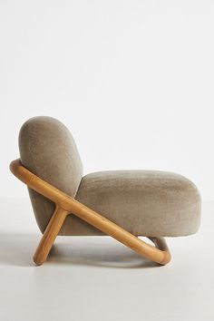 an upholstered lounge chair with wooden arms and foot rests against a white wall