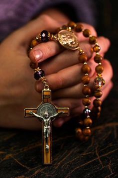 a person holding a rosary with a cross in the middle of their hand and an image of jesus on it