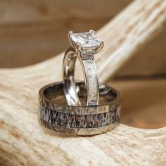 two wedding rings sitting on top of a piece of driftwood next to each other