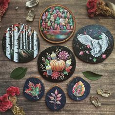 several decorated cookies sitting on top of a wooden table next to flowers and leaves in front of them