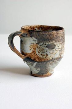 a brown and black cup sitting on top of a white table