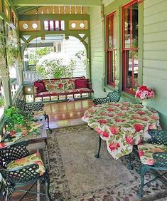 the porch is covered with floral tablecloths and chairs