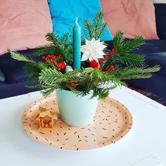 a table with a candle and flowers in a vase on top of a plate next to a blue couch