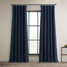 a blue curtain hanging in front of a window with wood flooring and white walls