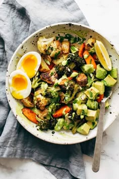 a bowl filled with broccoli, carrots and hard boiled eggs