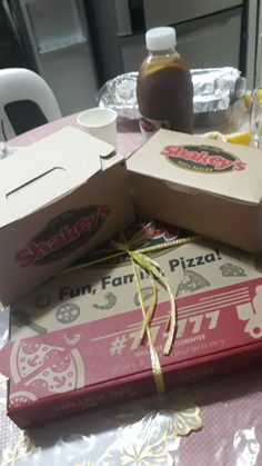 pizza boxes wrapped in yellow ribbon sitting on top of a pink tablecloth covered table