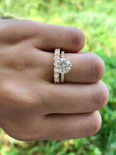 a woman's hand holding a ring with two stones on it and the middle finger