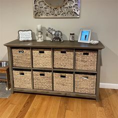 a wooden dresser with baskets on top and an elephant statue next to it in front of a mirror