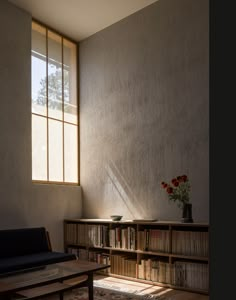 a living room with a couch, bookcases and a vase filled with flowers