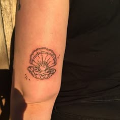 a woman's arm with a tattoo on it that has an image of a shell