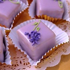 some purple desserts are sitting on a doily