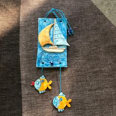 an ornament made to look like a sailboat and two fish on a string