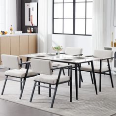 a dining room table with white chairs and black legs