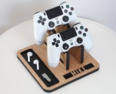 two white game controllers sitting on top of a wooden stand next to an earphone