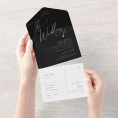 two hands holding up a black and white wedding card