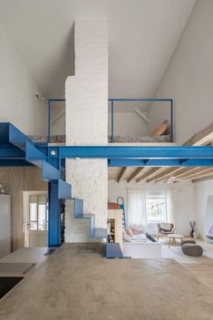 an open living room with blue stairs leading up to the second floor and loft above