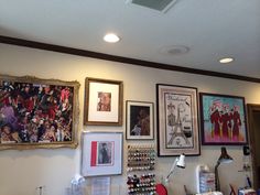 several framed pictures hang on the wall above a desk in a room with other items