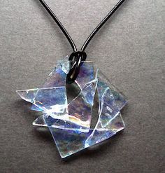 a piece of glass sitting on top of a black cord necklace with a square shape